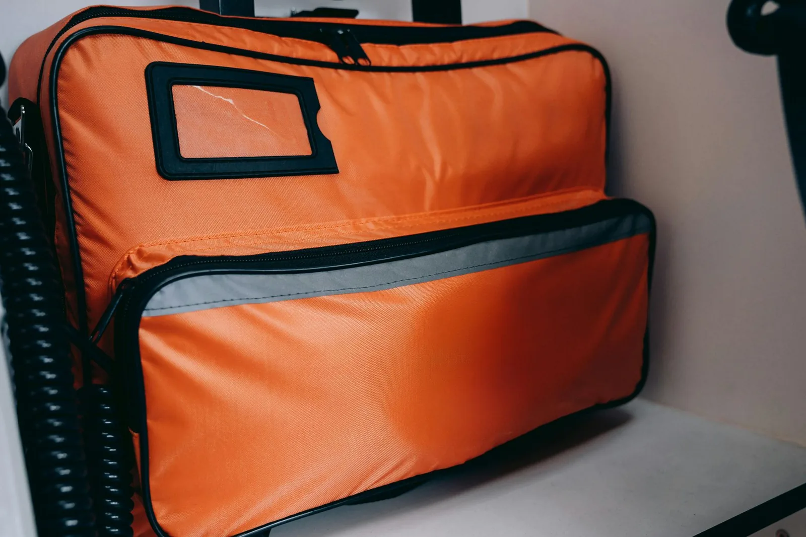 Kompaktes rotes Erste-Hilfe-Set liegt aufgeklappt neben einem Wanderrucksack am Wegesrand