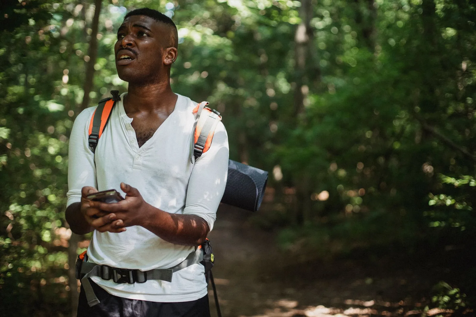 Wanderer prüft ein GPS-Navigationsgerät auf einem Bergpfad mit Blick ins Tal