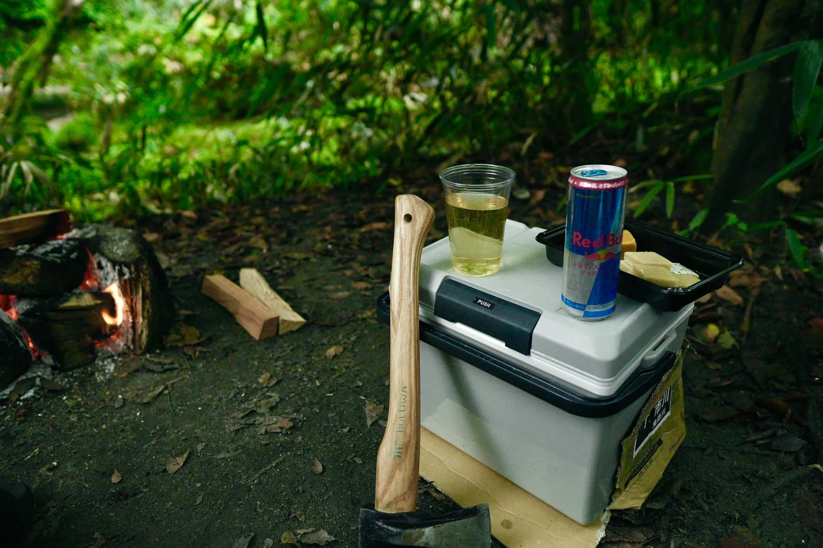 Kompressorkühlbox neben Campingausrüstung im Freien, geöffnet mit Getränken