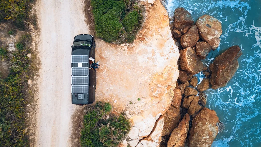 Campervan parked on dirt road by rocky ocean coastline