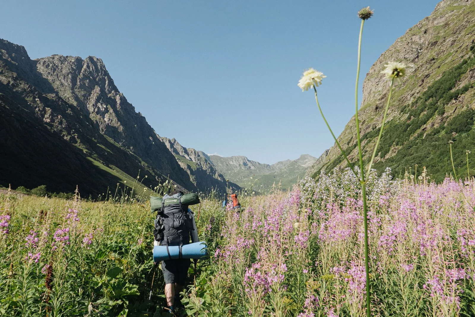 Wanderer mit großem Trekkingrucksack auf einem schmalen Bergpfad in den Alpen unterwegs