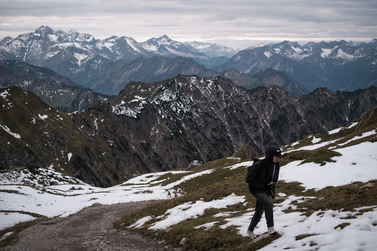 Wanderer trägt mehrere Kleidungsschichten übereinander auf einem Bergwanderweg